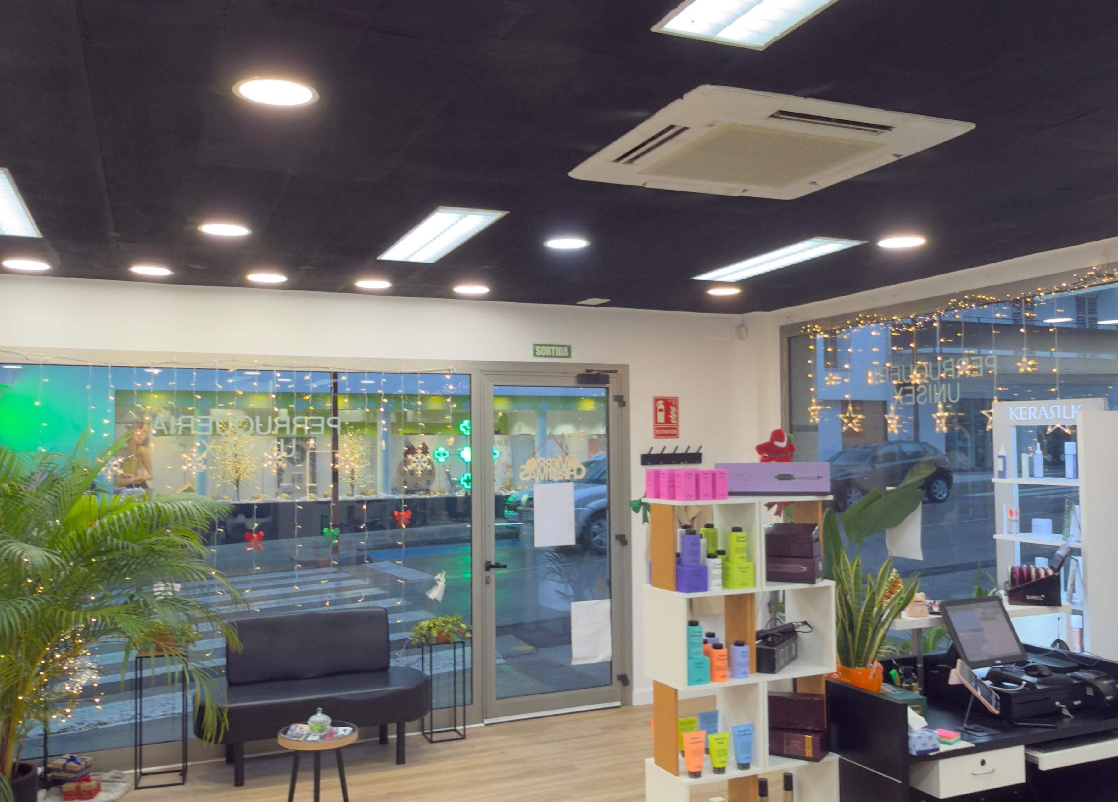 Moderno interior de Jhovana Hair Studio, L'escala, Catalunya, ES con decoración festiva y plantas verdes.