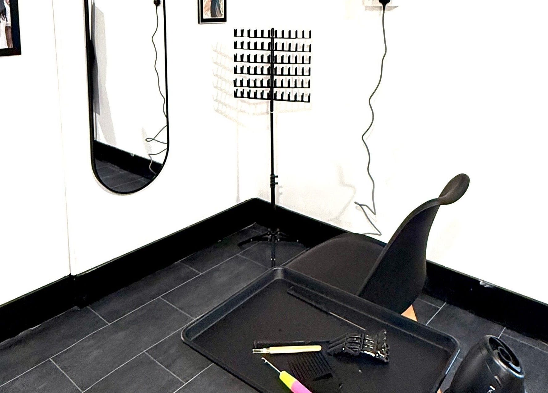 Modern salon station at Kulture Kurls, Whitley Bay, GB. Sleek styling tools and chair on dark tile.