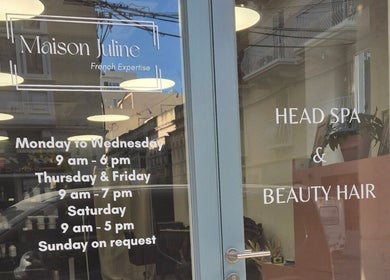 Entrance of Maison Juline in Il- GZIRA, MT, displaying salon hours on a glass door.