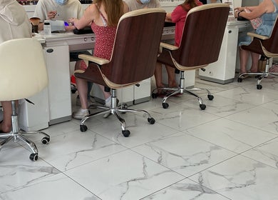 Customers receiving manicures at Maya Nails, Ashtead, England, GB. Modern salon with elegant decor.