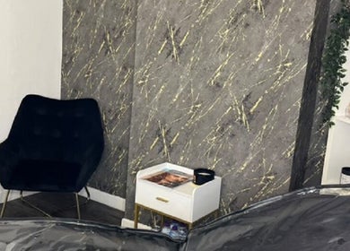 Elegant corner at Vasilica Manchester Aesthetics, Dukinfield, England, featuring a chair and marble wall.