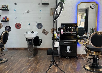 Interior elegante de Barber Shop Amin en Madrid, Comunidad De Madrid, ES con sillas de peluquería y espejo iluminado.