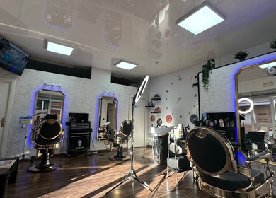 Interior elegante de Barber Shop Amin en Madrid, Comunidad De Madrid, ES con sillas doradas y espejos iluminados.