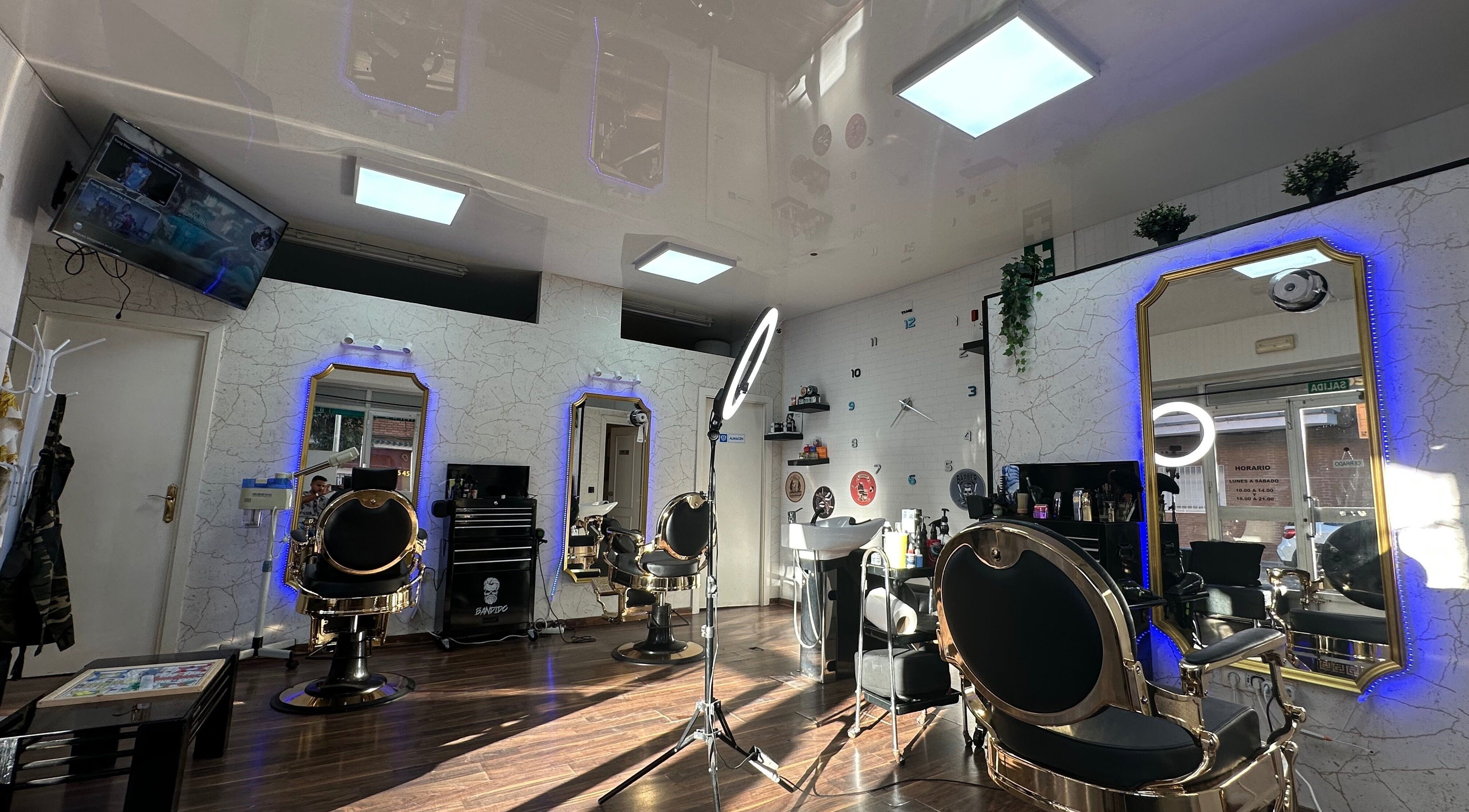 Interior elegante de Barber Shop Amin en Madrid, Comunidad De Madrid, ES con sillas doradas y espejos iluminados.