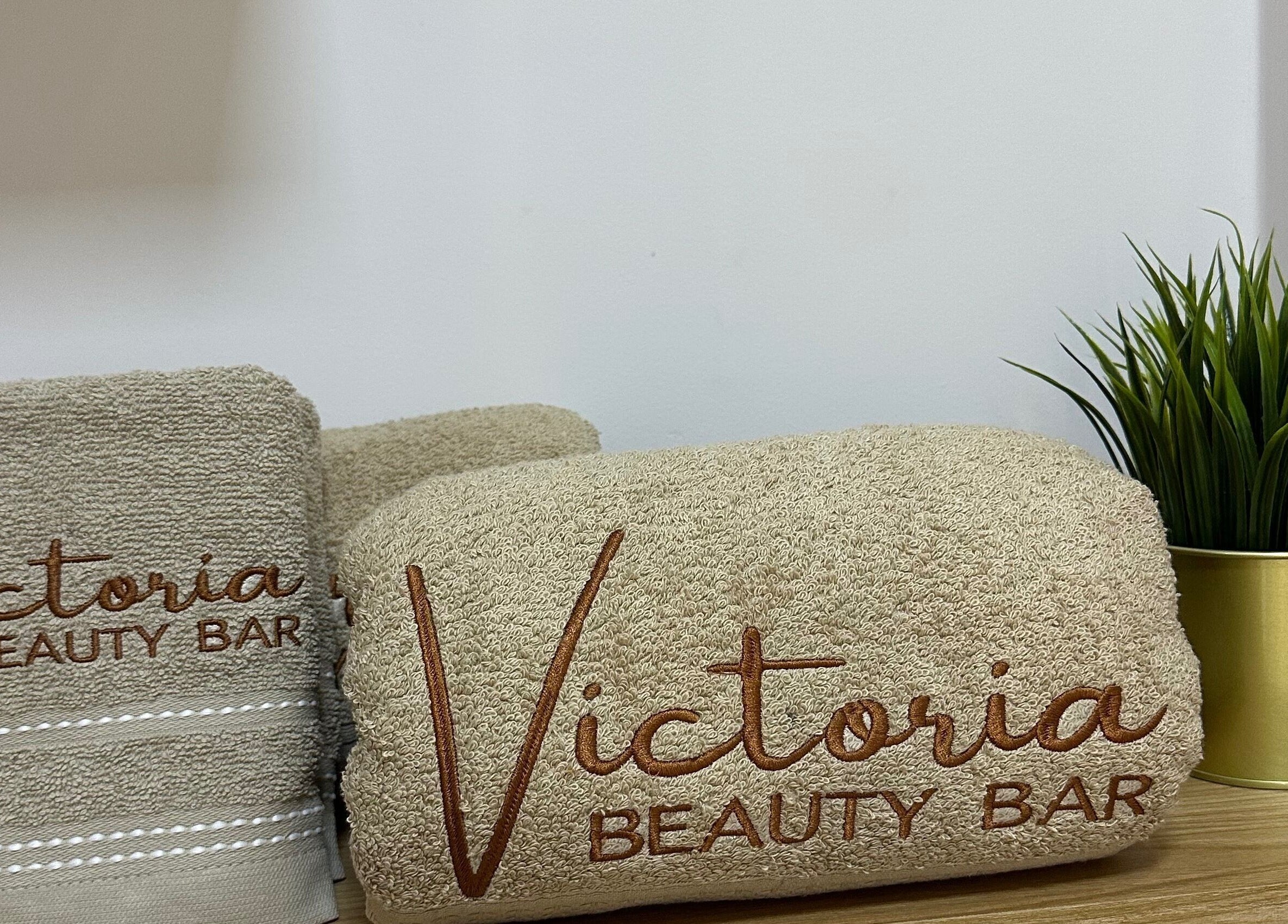 Toallas bordadas con Victoria Beauty Bar en Guadalajara De Buga, Valle Del Cauca, CO junto a una planta.