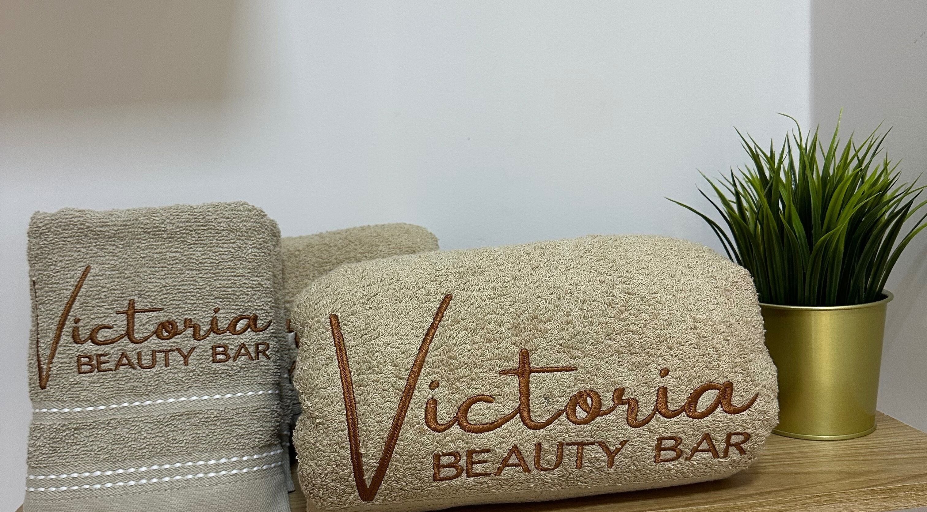 Toallas bordadas con Victoria Beauty Bar en Guadalajara De Buga, Valle Del Cauca, CO junto a una planta.