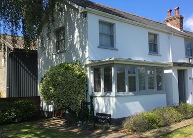 Exterior of Root and Remedy Wellness, a cottage-style venue in Purleigh, England, GB surrounded by lush greenery.
