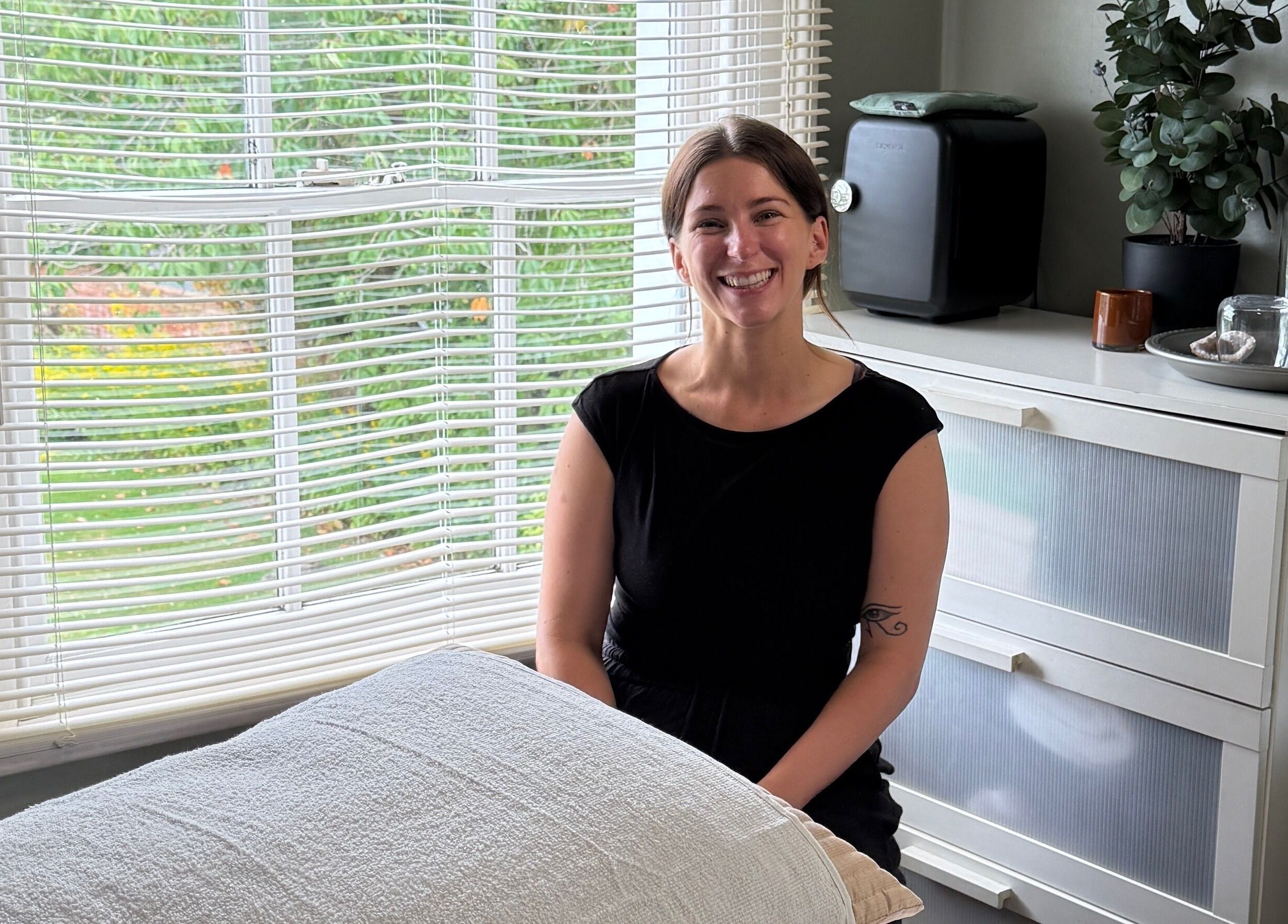 Smiling wellness therapist at Root and Remedy Wellness, Purleigh, England, GB in a tranquil room.