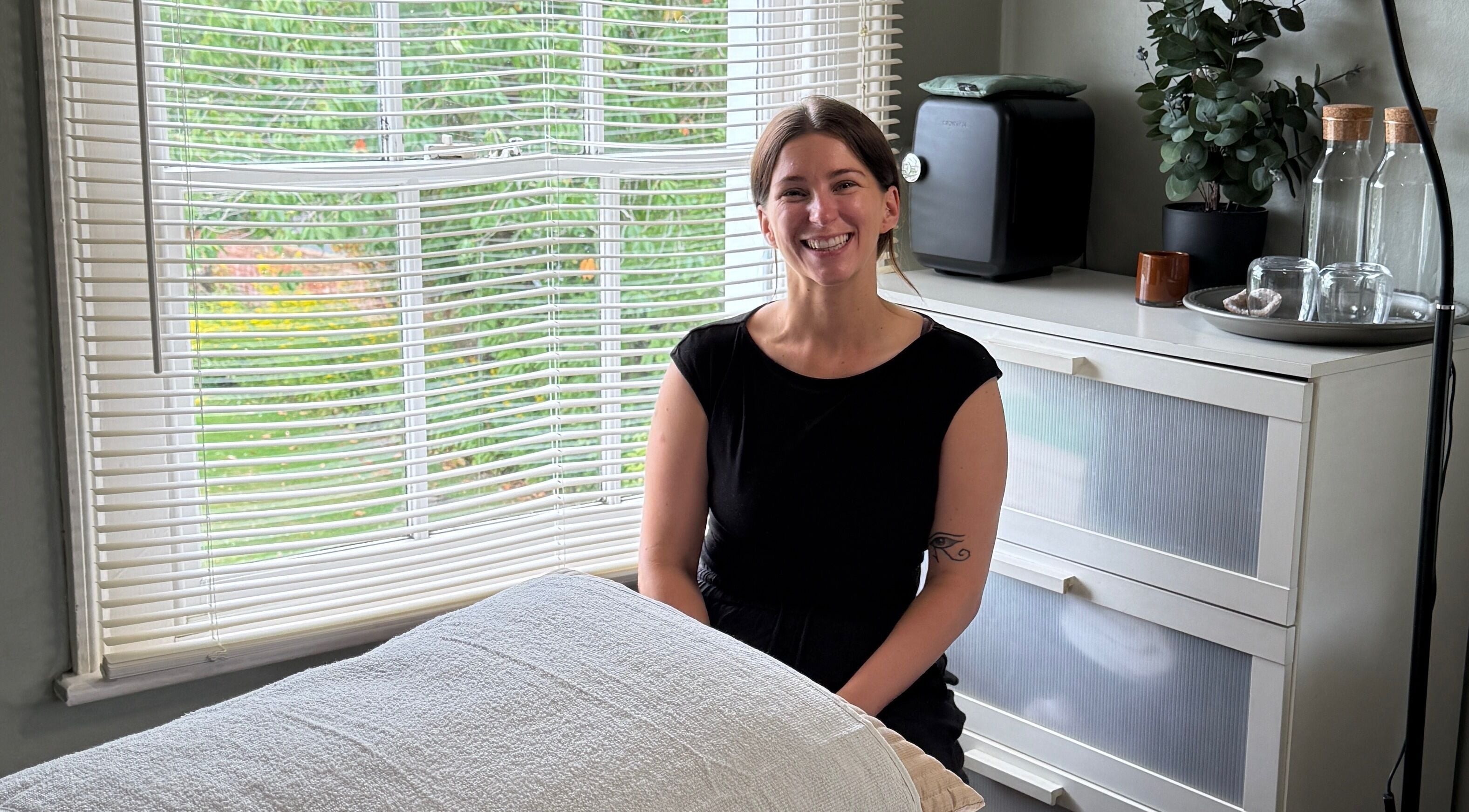Smiling wellness therapist at Root and Remedy Wellness, Purleigh, England, GB in a tranquil room.