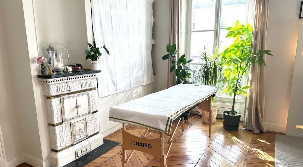 Salle de massage lumineuse à Aman Massage & Yoga, Paris, Île-de-france, FR, avec plantes et lumière naturelle.
