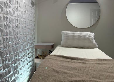 Tranquil treatment room at Nua Med Spa in Hialeah, Florida, US, featuring a textured wall and cozy bed.