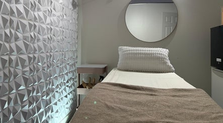 Tranquil treatment room at Nua Med Spa in Hialeah, Florida, US, featuring a textured wall and cozy bed.