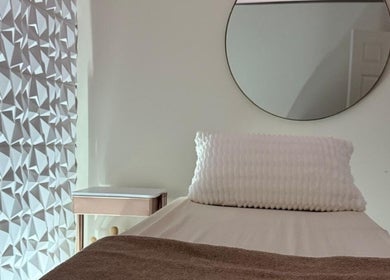 Calm treatment room at Nua Med Spa, Hialeah, Florida, US with textured wall and modern mirror.