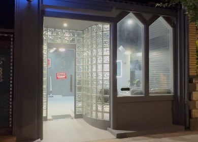 Fachada iluminada de Cuts, Tudela, Navarra, ES, mostrando diseño de vidrio moderno y acogedor.