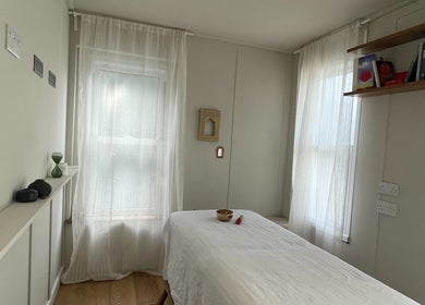 Calm massage room at FOLK, Perranporth, England, GB with a table, soft lighting, and bookshelves.