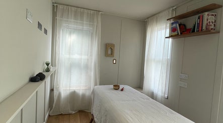 Calm massage room at FOLK, Perranporth, England, GB with a table, soft lighting, and bookshelves.