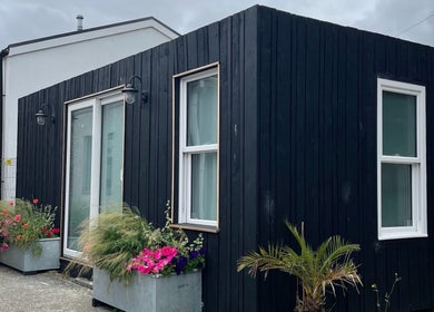 Contemporary FOLK venue with black wood siding and floral planters, Perranporth, England, GB.
