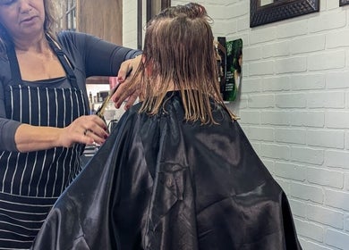 Jane hairstylist expertly cutting hair at her salon in Hamilton, Ontario, CA, ensuring a precise finish.