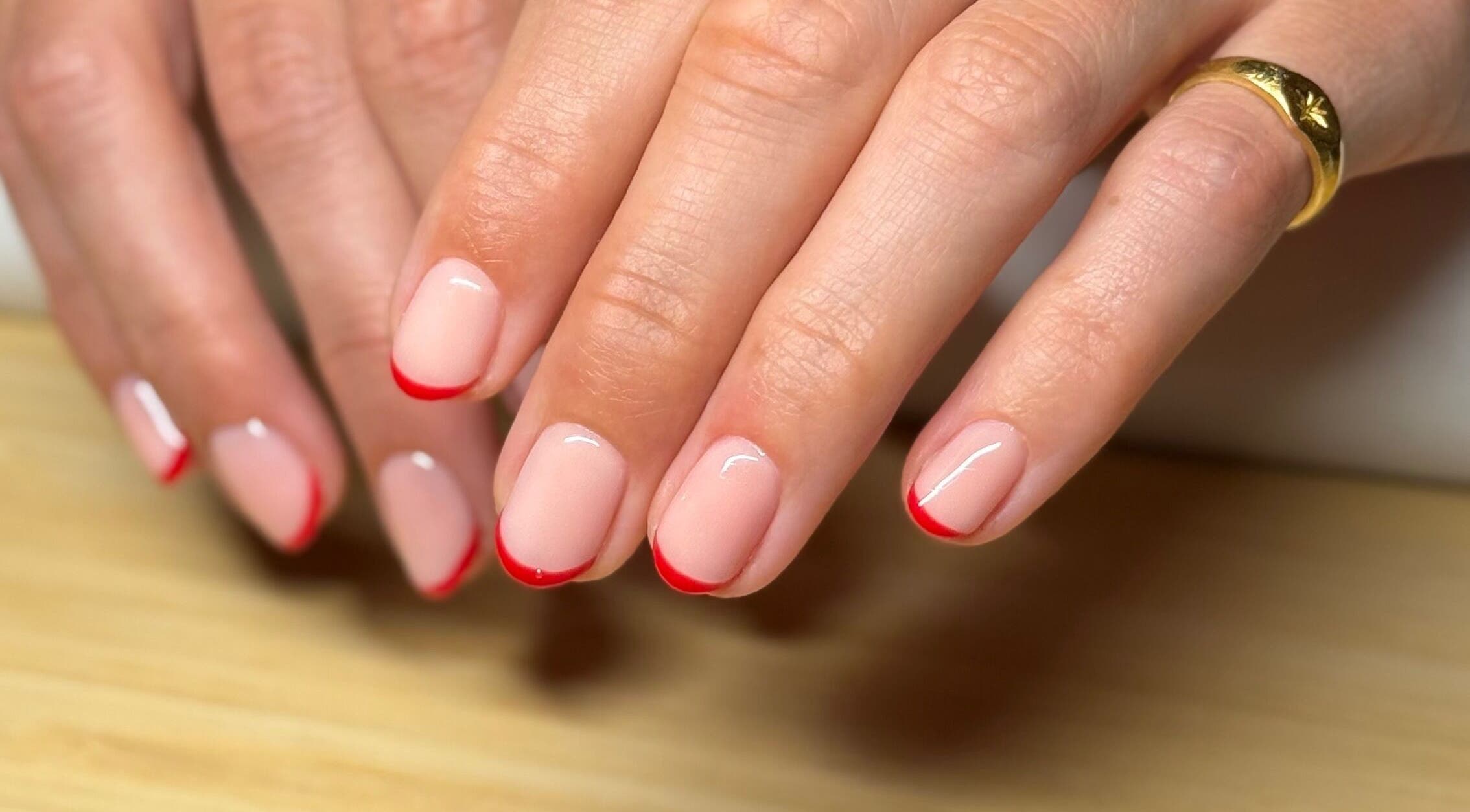 Elegant nude nails with red tips at Mano Mona Nails, Bondi Beach, New South Wales, AU.