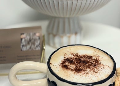 Cup of cappuccino at Desert Chic Hair, Urangan, Queensland, AU. Cozy ambiance with salon card in background.
