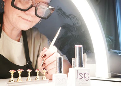 Nail technician at Ever Luxe Nails in Bilston, Scotland, creating intricate designs under a bright light.