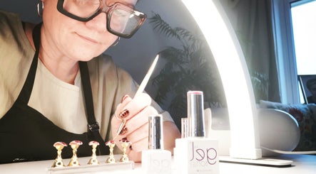Nail technician at Ever Luxe Nails in Bilston, Scotland, creating intricate designs under a bright light.