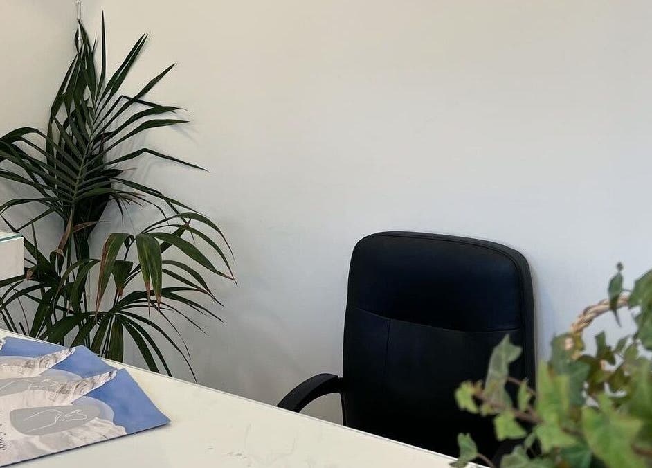 Inviting reception area at Aestheticare, Τριοβάσαλος, GR, featuring a lush potted plant and sleek black chair.