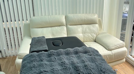 Relaxing massage area with leather sofa at EmpowerBeauty, Loughor, Wales, GB for wellness and tranquility.