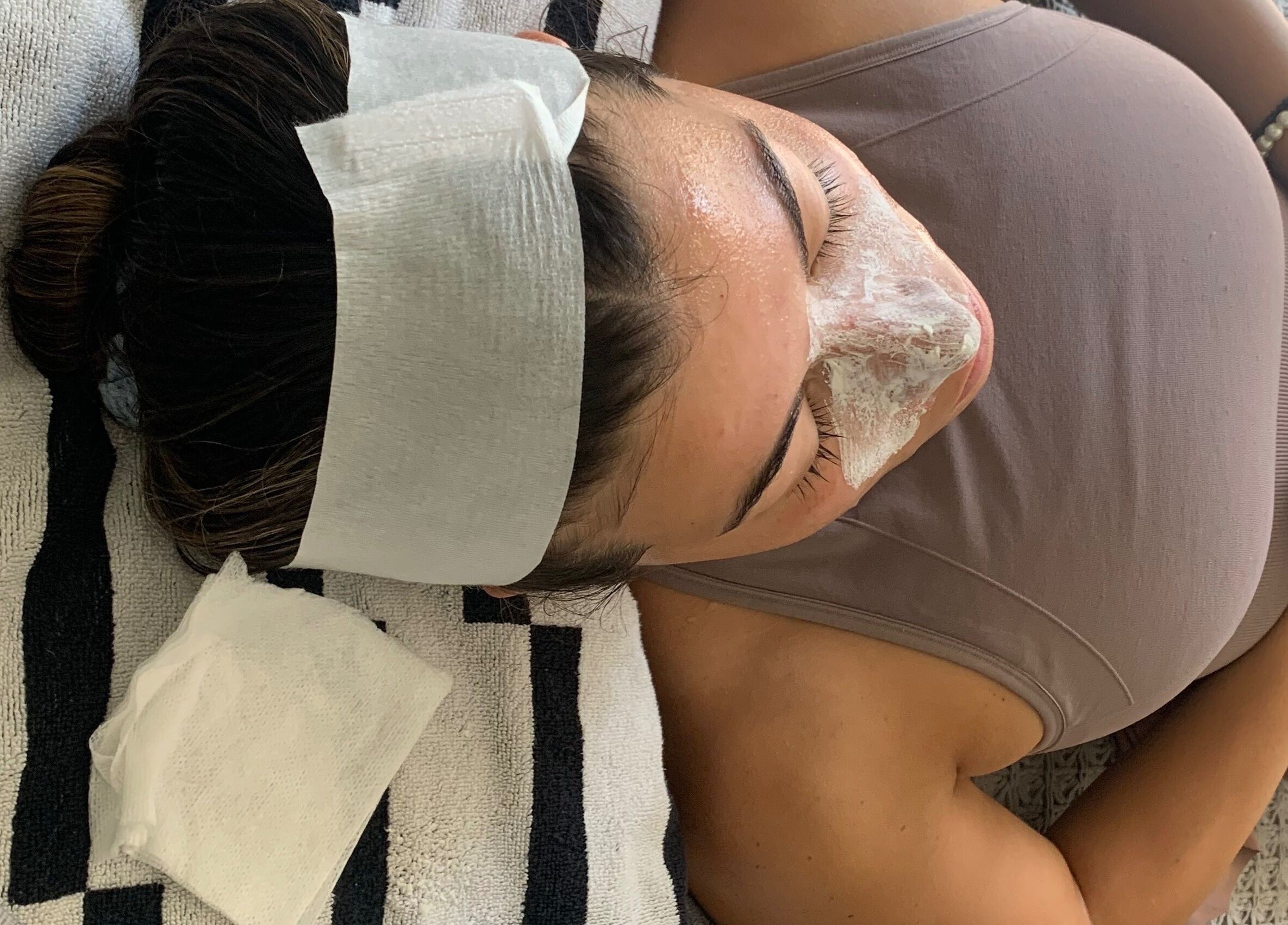 Woman receiving a facial treatment at Peach & Fox in New York, New York, US, lying on a spa bed.