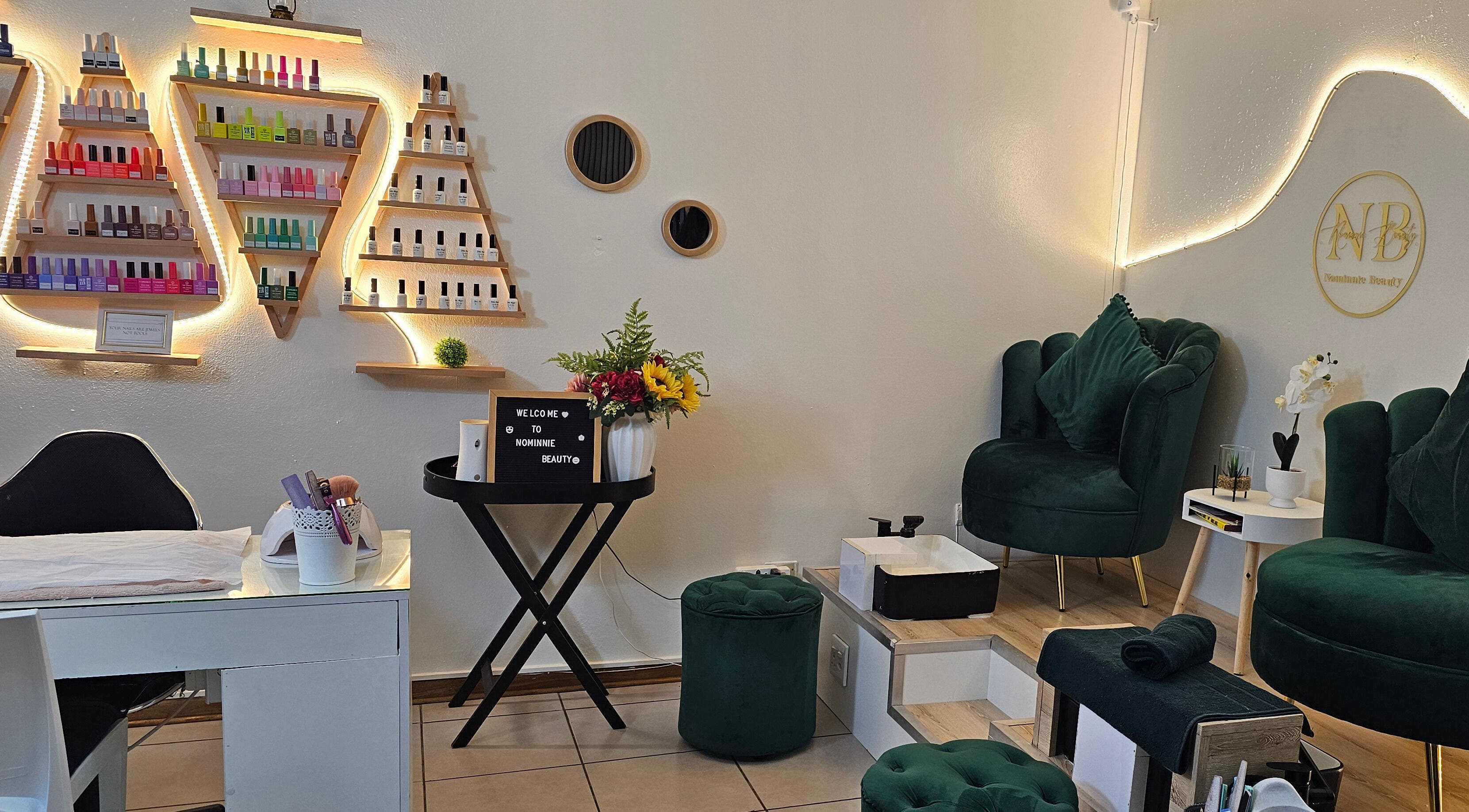 Modern beauty lounge at Nominnie Beauty in Bloemfontein, Free State, ZA with plush green chairs and nail polish display.