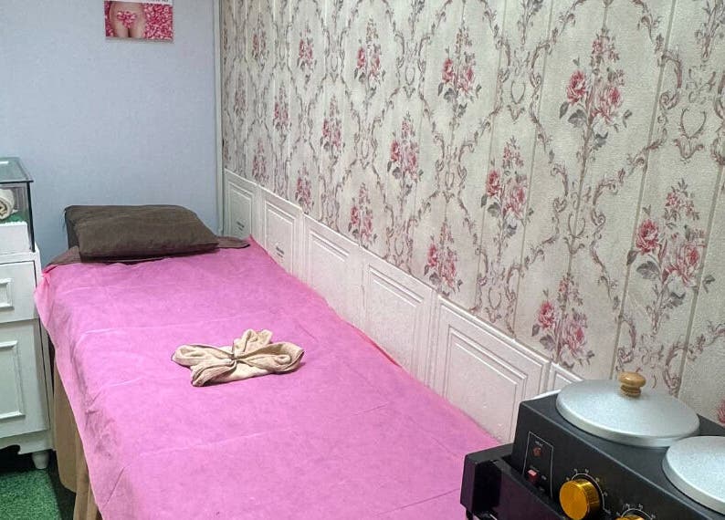 Treatment room at Riviea Beauty Salon, Wan Chai, HK. Features a pink bed, floral wallpaper, and spa amenities.
