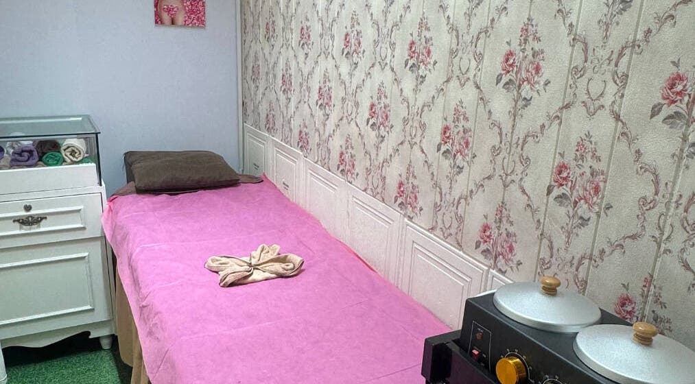 Treatment room at Riviea Beauty Salon, Wan Chai, HK. Features a pink bed, floral wallpaper, and spa amenities.