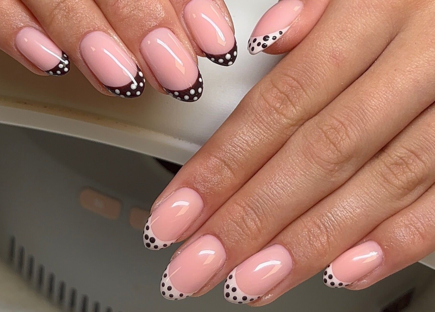 Polished by Asha in Haywards Heath, England, GB showcases elegant pink nails with black and white dot accents.
