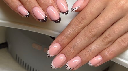 Polished by Asha in Haywards Heath, England, GB showcases elegant pink nails with black and white dot accents.