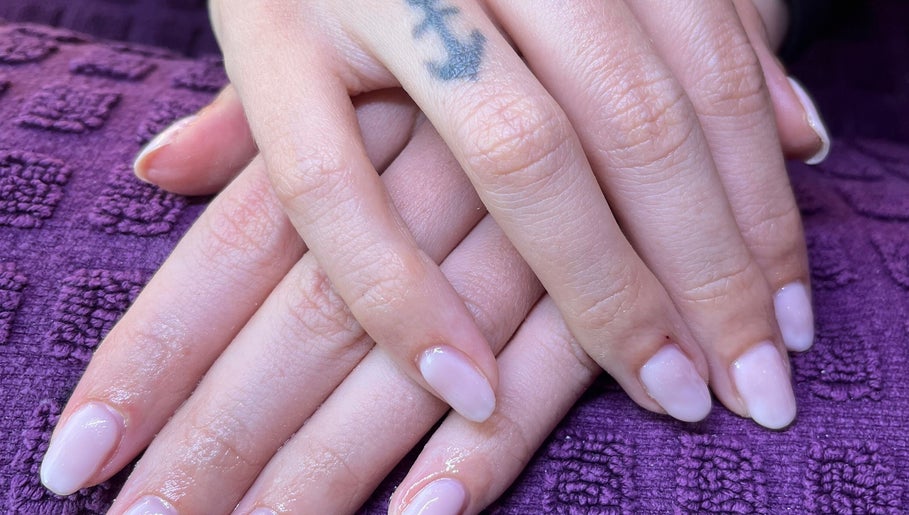 Freshly manicured hands with pale nails at Polished by Molly, Hedge End, England, GB on a purple textured cloth.