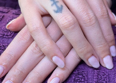 Freshly manicured hands with pale nails at Polished by Molly, Hedge End, England, GB on a purple textured cloth.