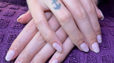 Freshly manicured hands with pale nails at Polished by Molly, Hedge End, England, GB on a purple textured cloth.