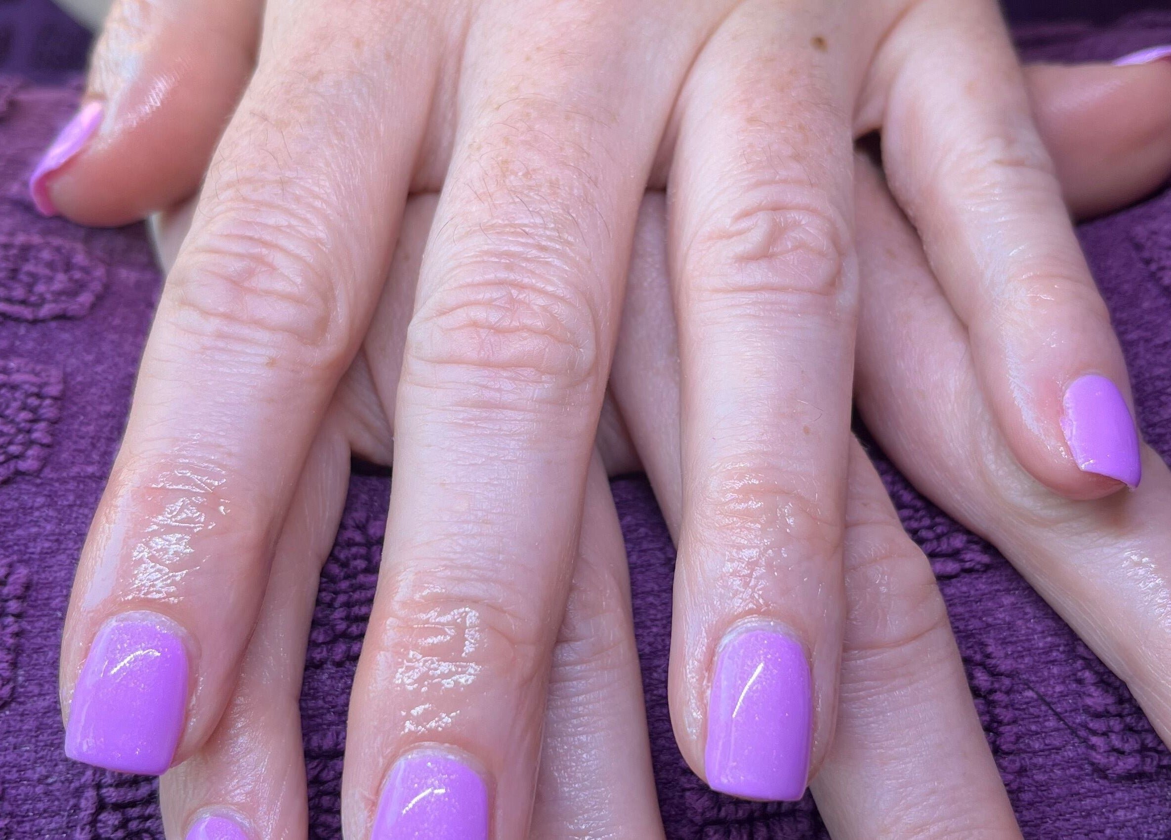 Lavender manicured nails by Polished by Molly in Hedge End, England, GB, resting on a textured purple towel.