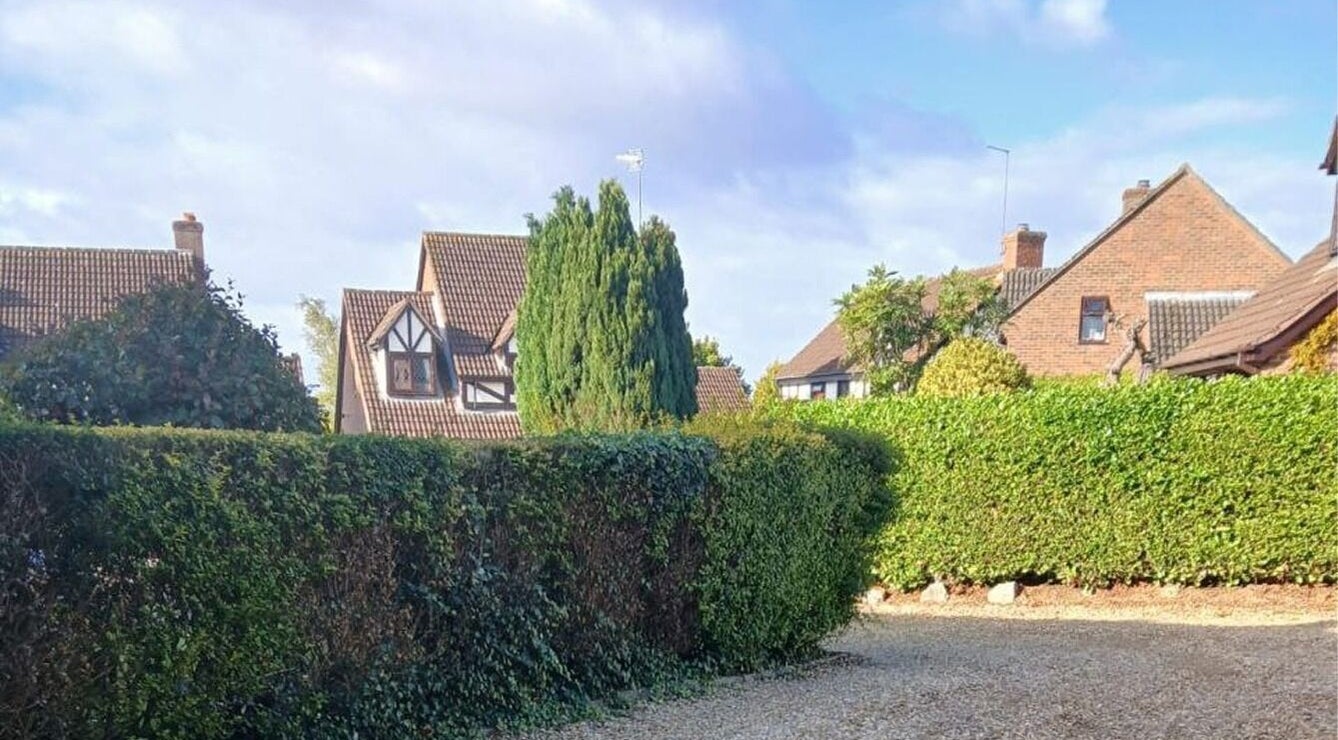 Picturesque view of quaint houses and lush hedges near Facial Massage Aigul, Northampton, England, GB.