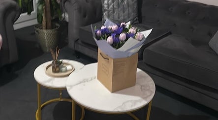 Sophisticated lounge area at Hair By Amina in London, England, GB, featuring a bouquet on stylish marble tables.