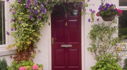 Charming red door with floral decor at Nails by Megan Caroline, Ballymena, Northern Ireland, GB.