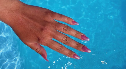 Sparkling pink nails by Nails by Megan Caroline in Ballymena, Northern Ireland, GB against a blue background.