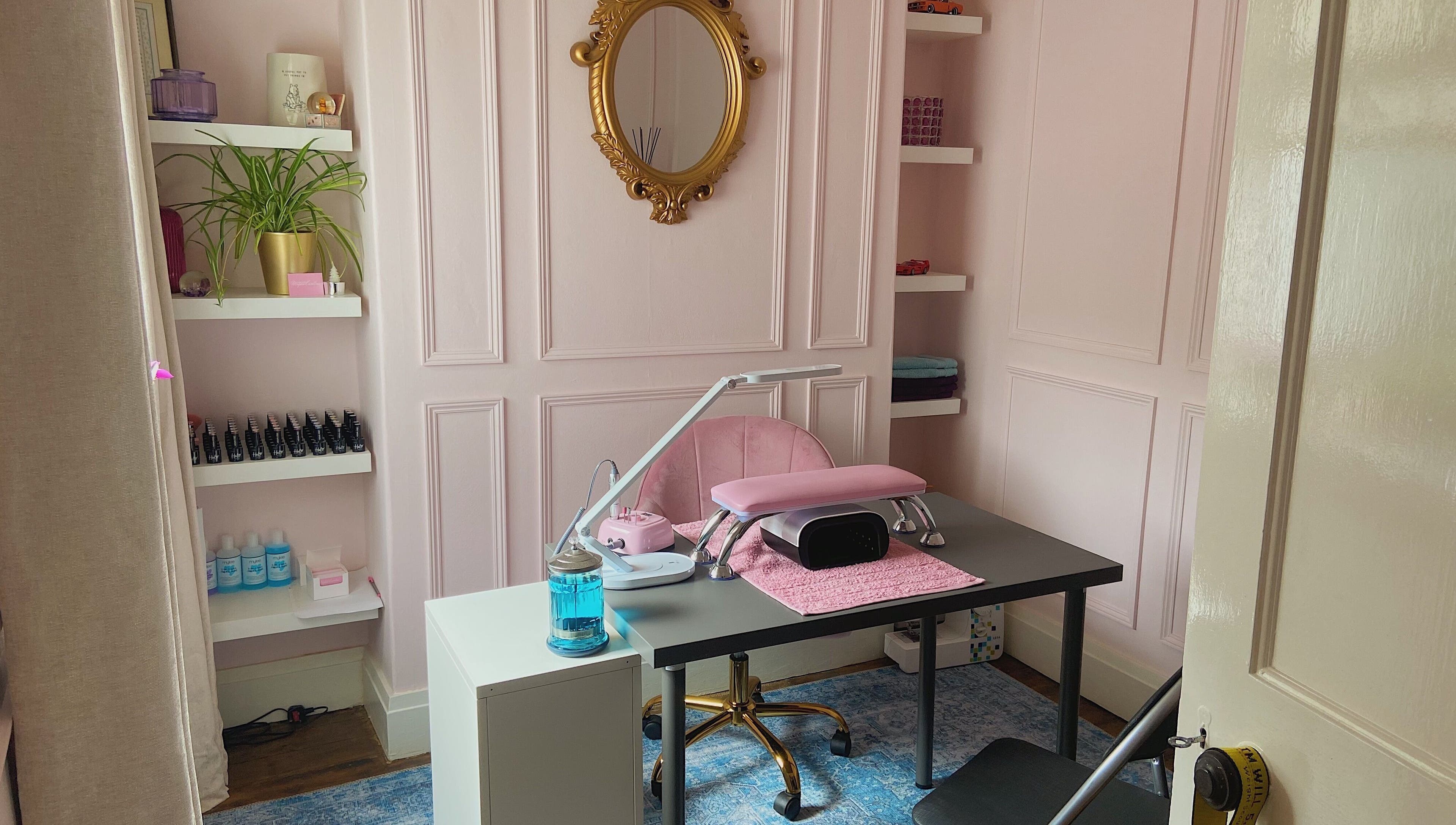 Elegant nail salon desk at Nails by Megan Caroline, Ballymena, Northern Ireland, GB with pink decor and gold mirror.