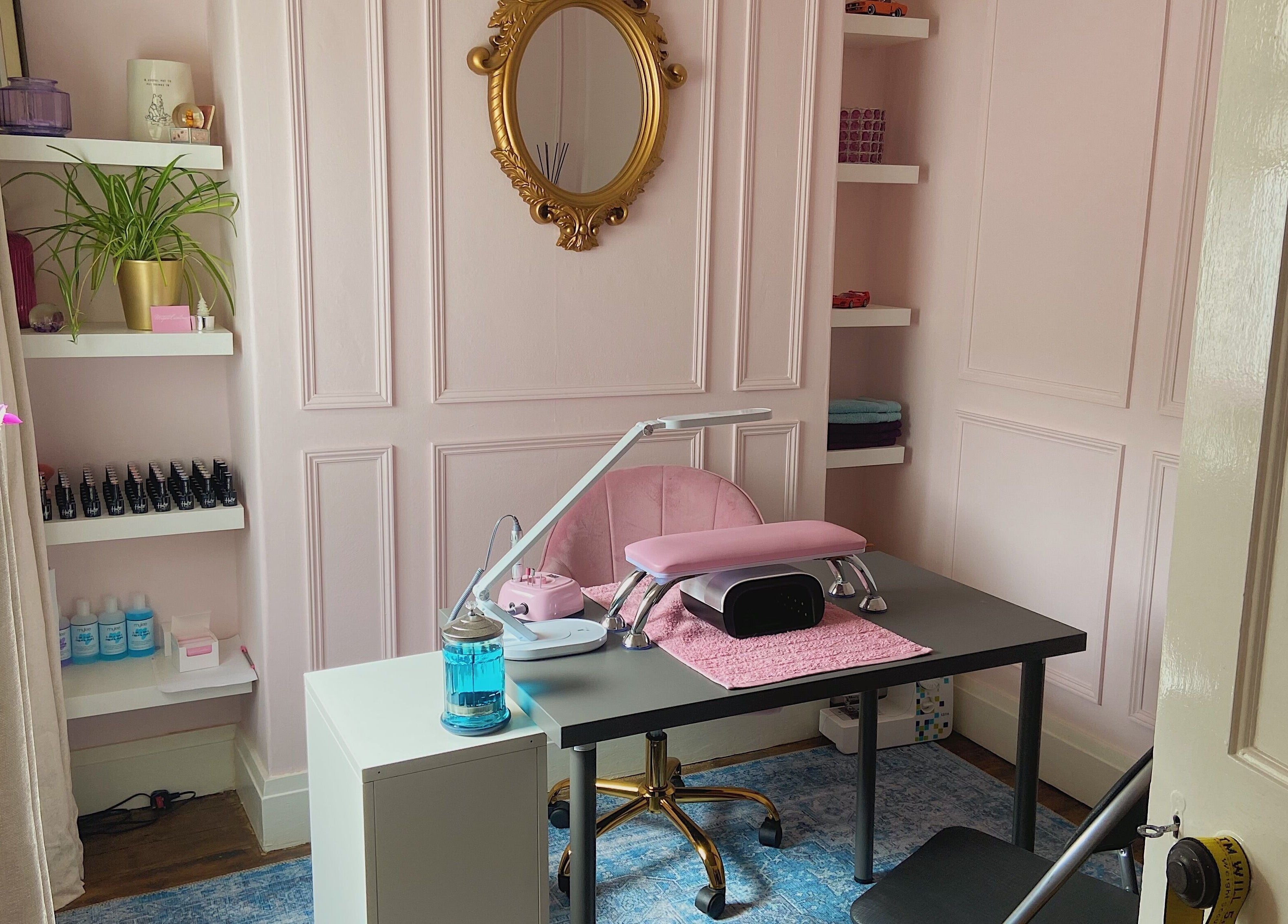 Elegant nail salon desk at Nails by Megan Caroline, Ballymena, Northern Ireland, GB with pink decor and gold mirror.