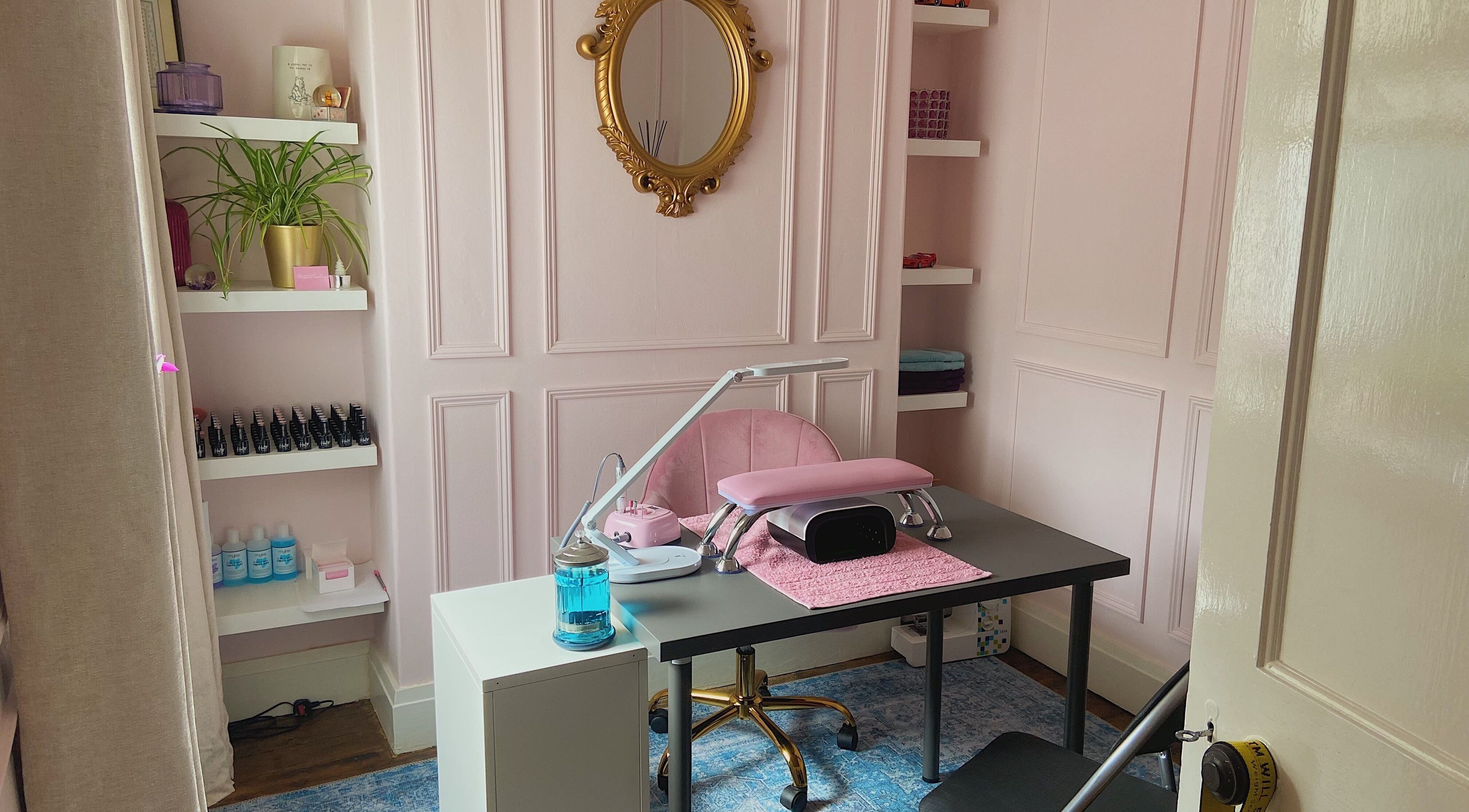 Elegant nail salon desk at Nails by Megan Caroline, Ballymena, Northern Ireland, GB with pink decor and gold mirror.