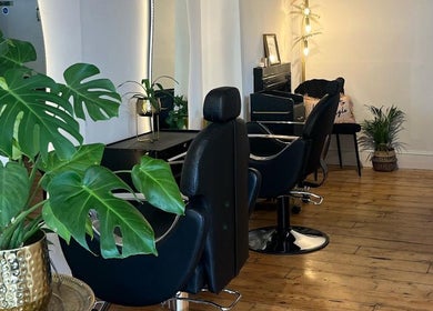 Sleek interior of Joshua Levi Hair in London, England, GB with stylish black chairs and lush plants.