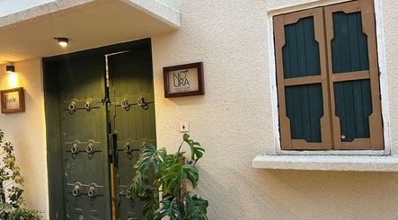 Entrance of Glowin Salon at Abha, Al Athar 7507, SA, featuring a stylish door and lush greenery.