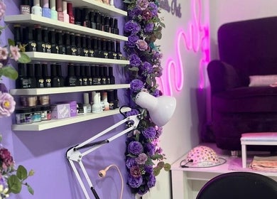 Estante de esmaltes en Tayanara Beauty Center en Panamá, PA, decorado con flores púrpuras vibrantes.