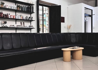 Interior del salón Kate Karlsson en Cabañas, con sofá negro y estantes de productos de belleza.