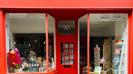 Front view of TULA AYURVEDA's inviting red façade storefront in Frome, England, GB, showcasing wellness products.